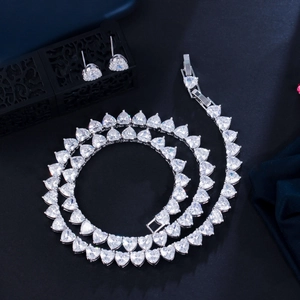 Detail view of silver heart-shaped zircon necklace and stud earrings set on a jewelry box