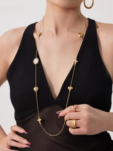 Detail van een gelaagde gouden rvs trui-ketting met hart- en kruisbedels
