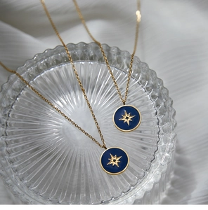 Detailed view of two blue enamel compass star pendants on gold stainless steel necklaces