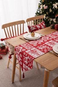 Dettaglio del runner da tavola jacquard e federe con renne e nappe decorative natalizie