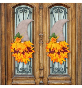 Detail of two autumn gnome hangers with maple leaves and flowers on a rustic wooden door