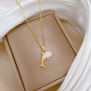 Detailed shot of golden dolphin pendant with shell inlay and shimmering crystal accents