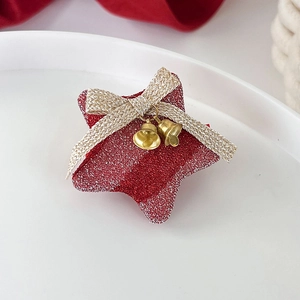 Détail de pince à cheveux étoile rouge pailletée avec nœud doré et clochettes métal