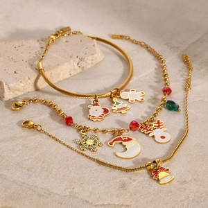 Golden Christmas jewelry set featuring festive enamel charms on stylish steel bracelets