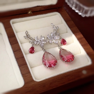 Macro shot of silver flower earrings with pink gradient teardrop crystals in wooden box