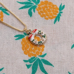 Golden Christmas wreath necklace with white enamel and colorful crystals on fabric
