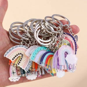 Macro detail of hand-held acrylic rainbow keychain with metal ring and white clouds