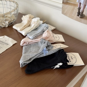 Detail of soft knit mid-calf socks with back bows displayed on a rustic wood surface