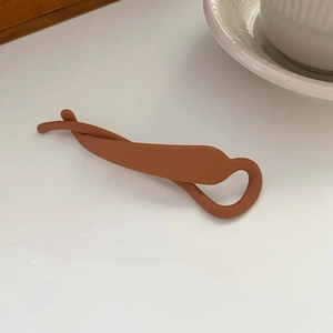 Détail d'une pince banane marron pour queue de cheval sur un bureau blanc très propre