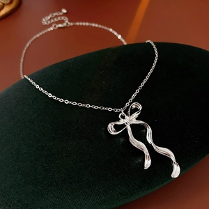 Gros plan d'un collier avec pendentif nœud argenté sur un présentoir en velours vert