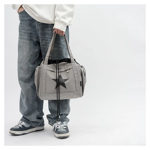 Detail of grey crossbody tote with star logo and black drawstring closure on model