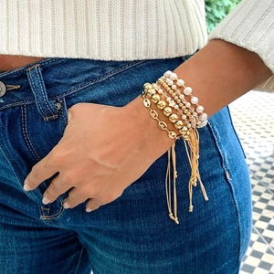 Detail of layered bohemian bracelets with pearls and gold beads on a wrist