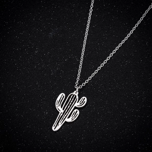 Macro shot of silver cutout cactus pendant and chain on a dark shimmering background