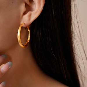 Detail of large 18k gold plated brushed hoop earring worn on model for premium style