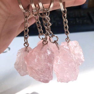 Natural raw pink crystal stone keychain set with silver metal ring on desk