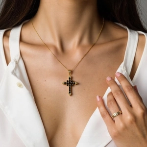 Macro view of cross pendant with black zircon inlays and delicate gold relief details
