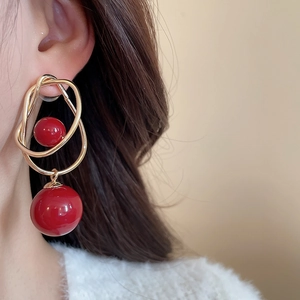 Detailed shot of red bead gold hoop earrings worn on ear showing elegant drop style