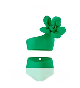 Detail of neon green one-shoulder swimsuit with 3D floral accent and high waist design