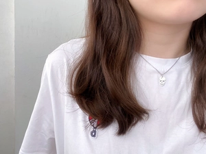 Close-up of minimalist silver skull pendant necklace worn on a woman neck for styling
