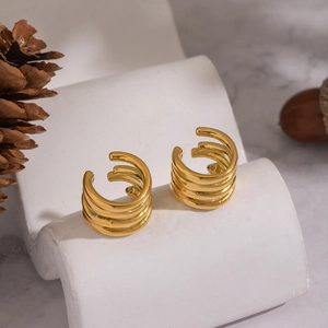 Three-layer gold geometric ear cuff set on white display with natural pine cone accents