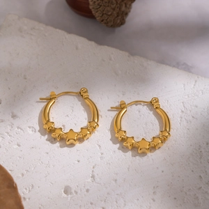 Detail shot of 18K gold-plated stainless steel star hoop earrings on a textured stone base