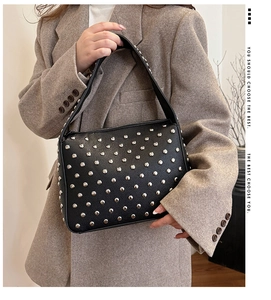 Detail of black lychee grain leather bag featuring silver rivet studs and top handle