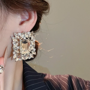 Macro close-up of a silver square rhinestone earring with leaf-shaped diamond accents
