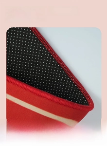 Macro detail of red carpet with non-slip dot plastic backing and reinforced stitched edges