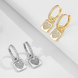 Close-up of gold and silver heart lock hoop earrings with shimmering pave-set crystals
