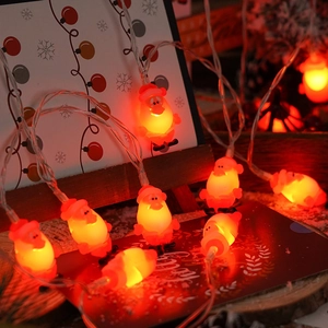 Macro view of warm glowing Santa Claus LED light string ornaments on a wooden base