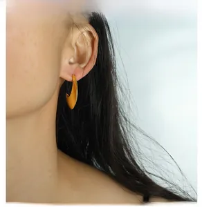 Close-up of elegant gold wide arc hoop earrings with a polished finish worn by a model