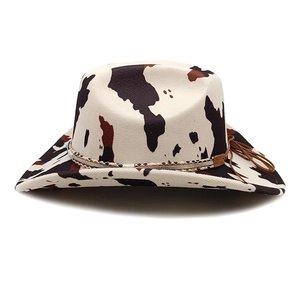 Close-up of cow print western cowboy hat with woven band and fringe tassel detail