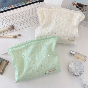 Détails du tissu en dentelle pailletée d'une trousse à maquillage crème et vert menthe
