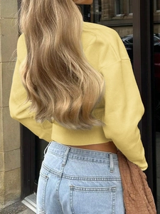 Rear view of cropped yellow long-sleeve knit sweater with ribbed cuffs and hem details