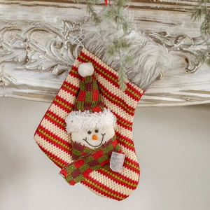 Knitted Christmas stocking with snowman appliqué hanging on a white mantel for festive decor