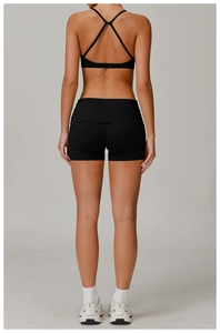 Detail of cross-back straps on black sports bra and high-waist fitness yoga shorts