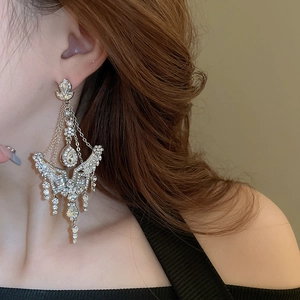 Close-up of sparkling waterdrop tassel earrings with rhinestones on a female model