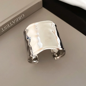 Detailed view of silver open cuff bracelet with hammered texture resting on a vintage book