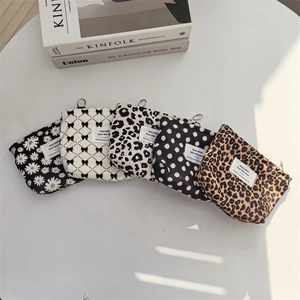 Detailed flat lay of corduroy lipstick pouches with daisy and leopard prints on a desk