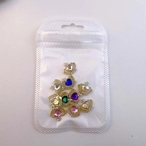 Macro shot of colorful crown nail charms with rhinestones in a transparent bag