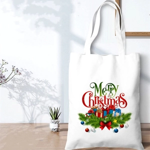 Detail of white canvas Christmas tote bag with Merry Christmas print on wooden table