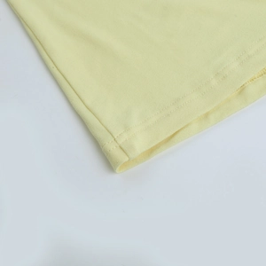 Détail de l'ourlet de la robe jaune clair avec coutures précises à double aiguille