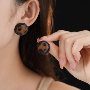Gros plan d'un mannequin portant des boucles d'oreilles léopard rondes en argent