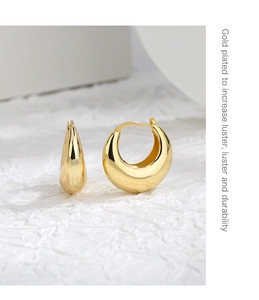 Detail of gold-plated chunky C-hoop earrings featuring a high-luster polished finish