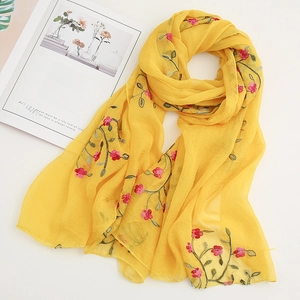 Detailed embroidery of pink flowers and green leaves on lightweight yellow chiffon fabric