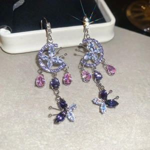 Detail view of silver drop earrings with purple butterfly crystals and crescent moons