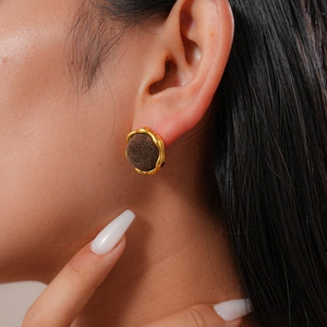 Close-up of elegant gold-rimmed brown flocking round stud earrings worn by a model