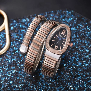 Macro shot of silver and rose gold snake-shaped watch with crystal bezel on blue sand