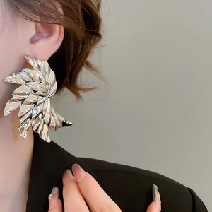 Detail of silver pleated wing earrings with metallic texture shown on a model