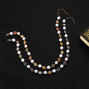 Detail of vintage flower necklaces with pearls and colorful rhinestones on black background